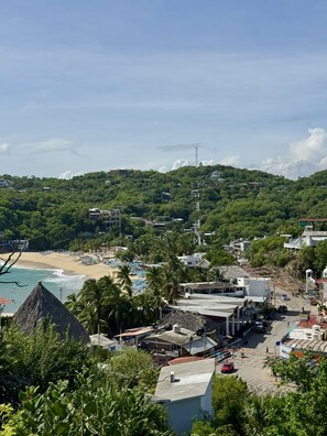 A coastal town with a beach, buildings, and lush greenery.