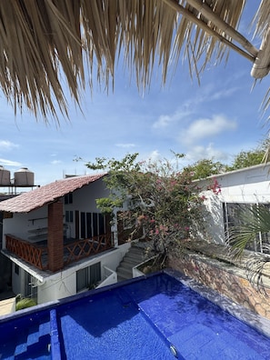 A residential area with a swimming pool, a house with a tiled roof, and a staircase leading to a balcony. - Ruby & Antonella (San Pedro Pochutla)