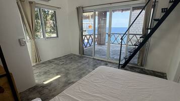 A room with a bed, a window, and a view of the sea.