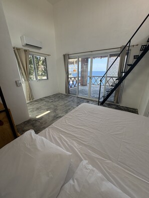 A room with a bed, a window, and a view of the sea.