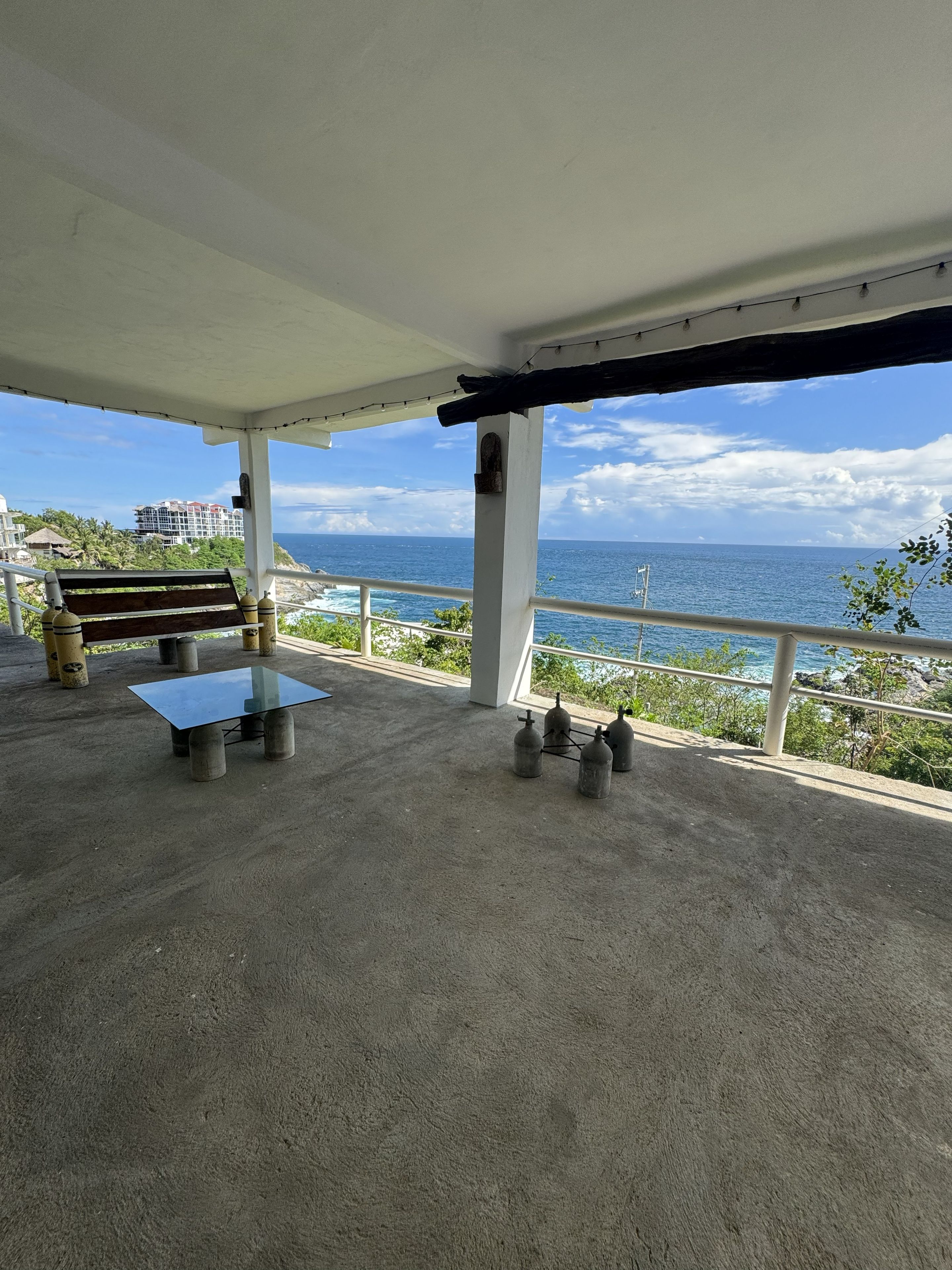 A covered outdoor area with a bench, a table, and gas cylinders.