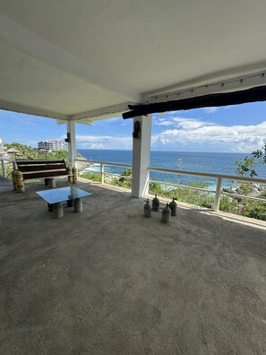 A covered outdoor area with a bench, a table, and gas cylinders. - Ruby & Antonella (San Pedro Pochutla)