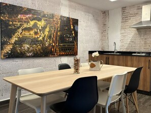 A modern kitchen with a wooden table, chairs, and a large painting on the wall. - Apto. Loft Tulum By Gyd (Tulum)