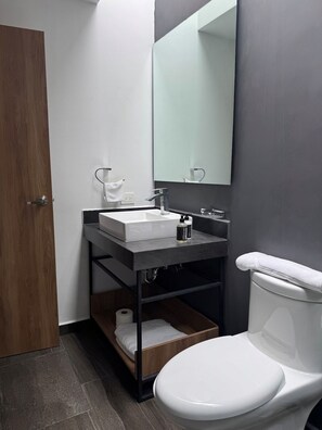 A modern bathroom with a white toilet, a sink with a mirror above it, and a towel rack. - Apto. Loft Tulum By Gyd (Tulum)
