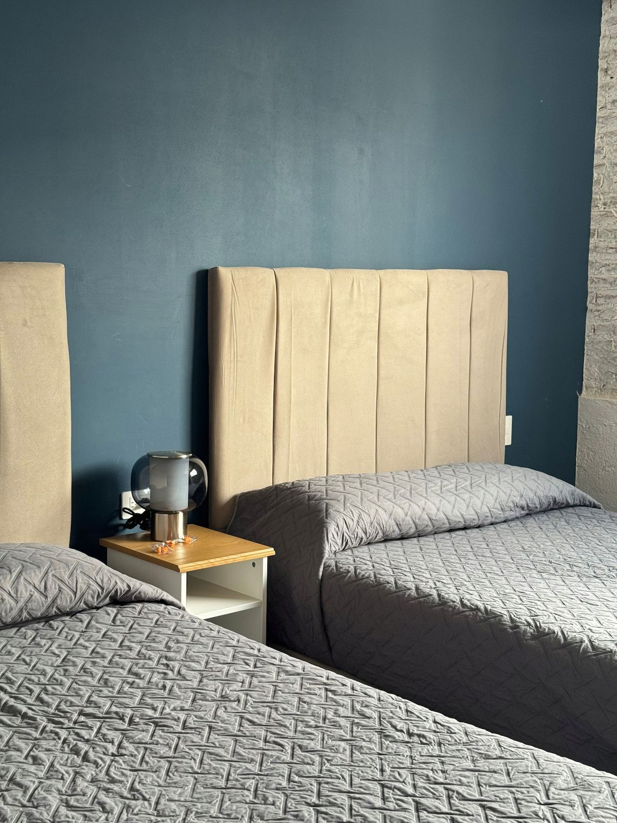Una camera d'albergo con un letto grande, un comodino con una lampada e un termosifone a parete.