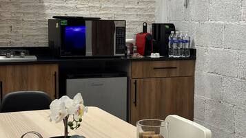 Una cucina con forno a microonde, macchina del caffè e bottiglie d'acqua sul piano di lavoro.