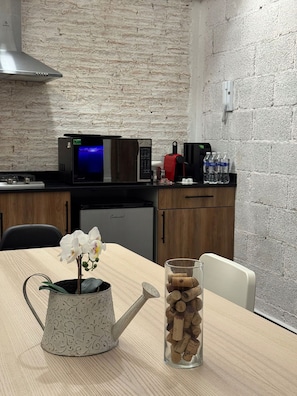 Una cucina con forno a microonde, macchina del caffè e bottiglie d'acqua sul piano di lavoro.