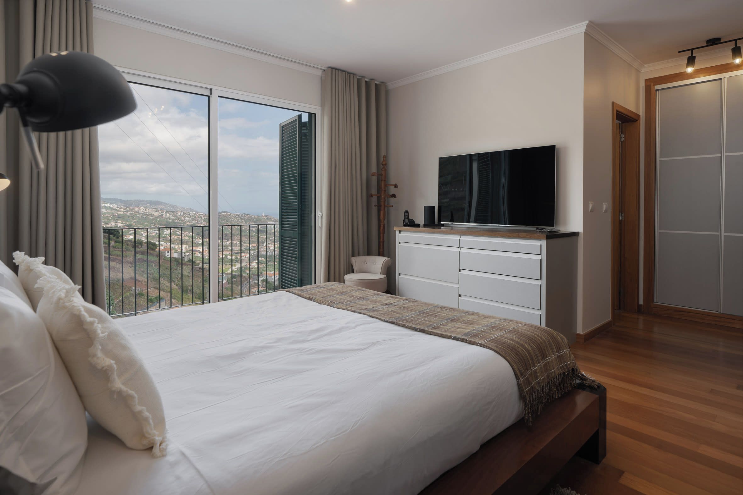 Une chambre avec un grand lit, une télévision et une vue sur la ville.