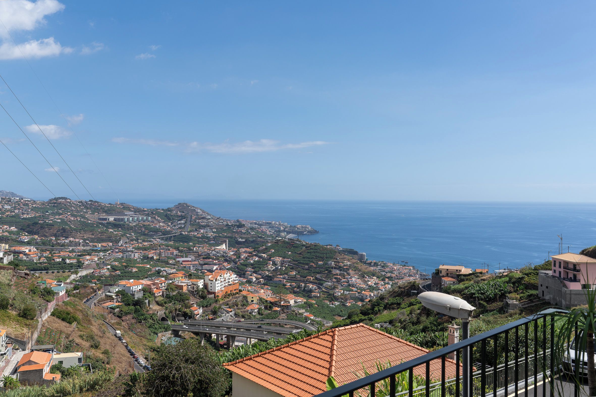 A coastal cityscape with a prominent bridge, terraced houses, and a clear view of the sea.