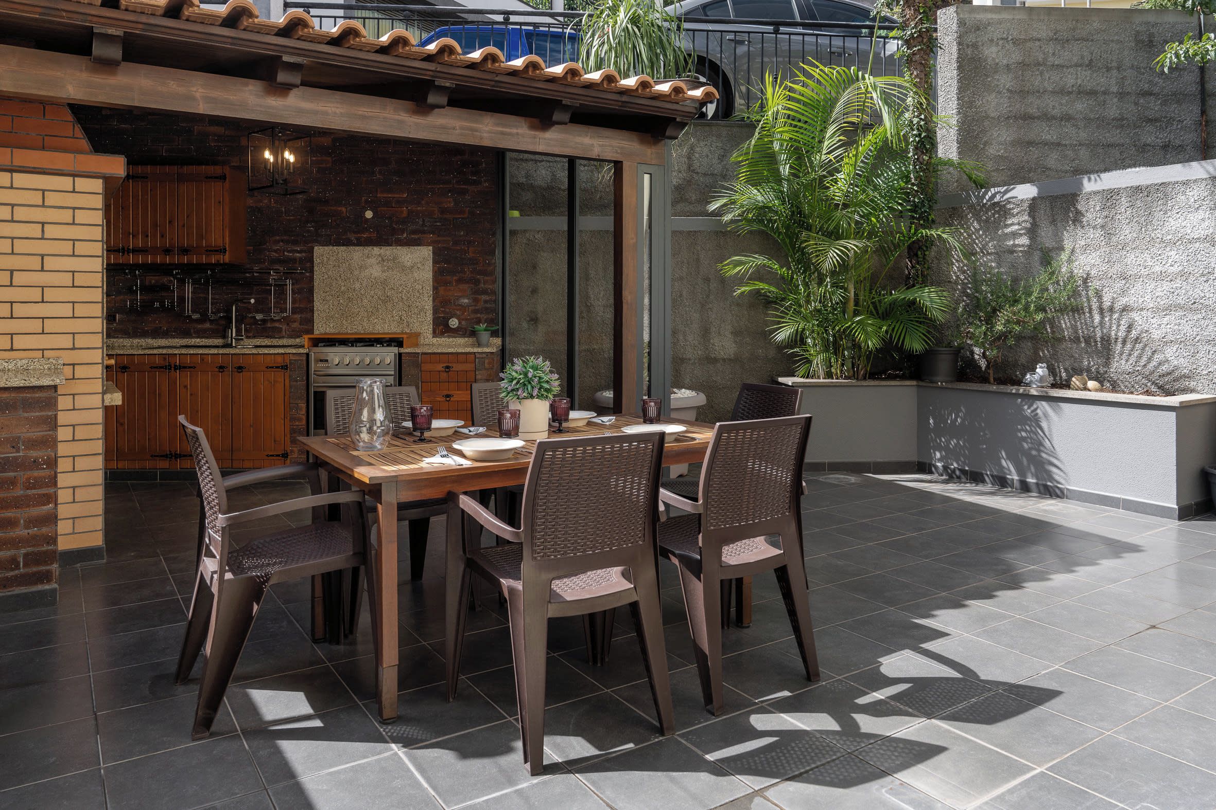 An outdoor dining area with a brick wall, a wooden table, and chairs.