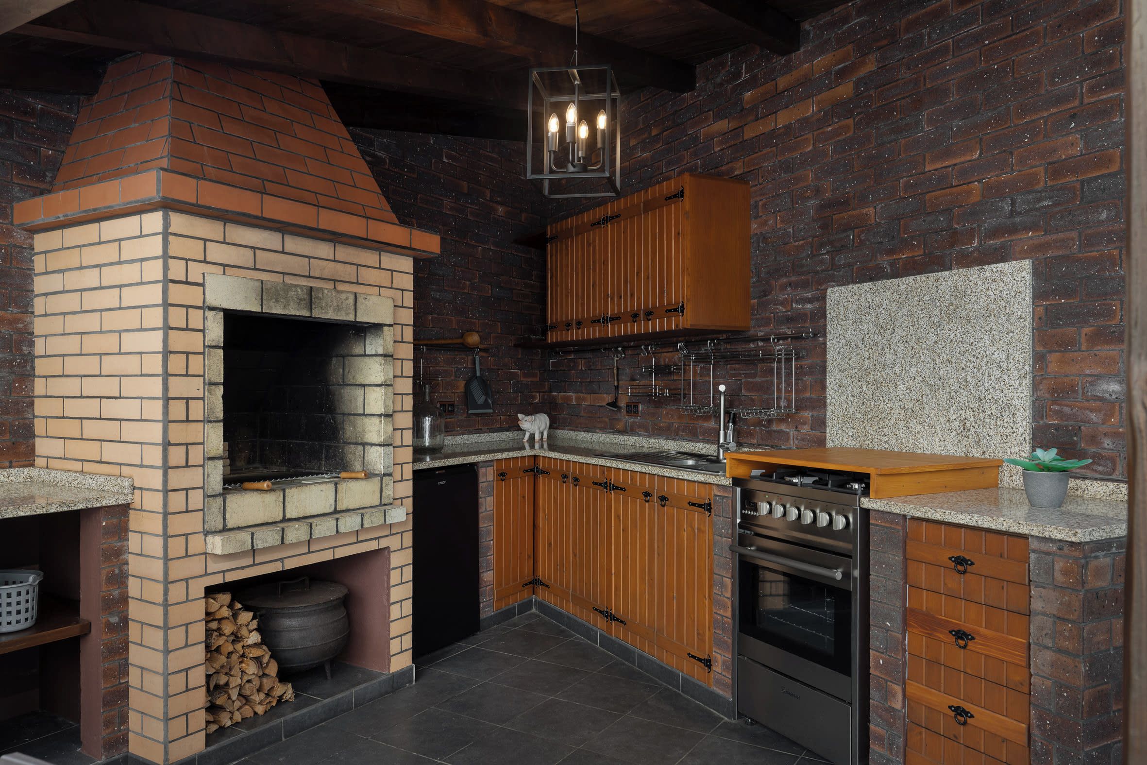 Une cuisine dotée d’un four en briques, de meubles en bois et d’une cuisinière intégrée.