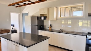 A kitchen with white cabinets, a black countertop, a built-in microwave, and a stove.