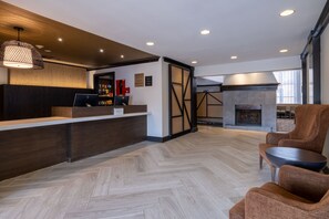 A modern reception area with a wooden reception desk, a fireplace, and seating. - Queen Studio w/ Free Breakfast, Pool & Fire Pit (Dublin)