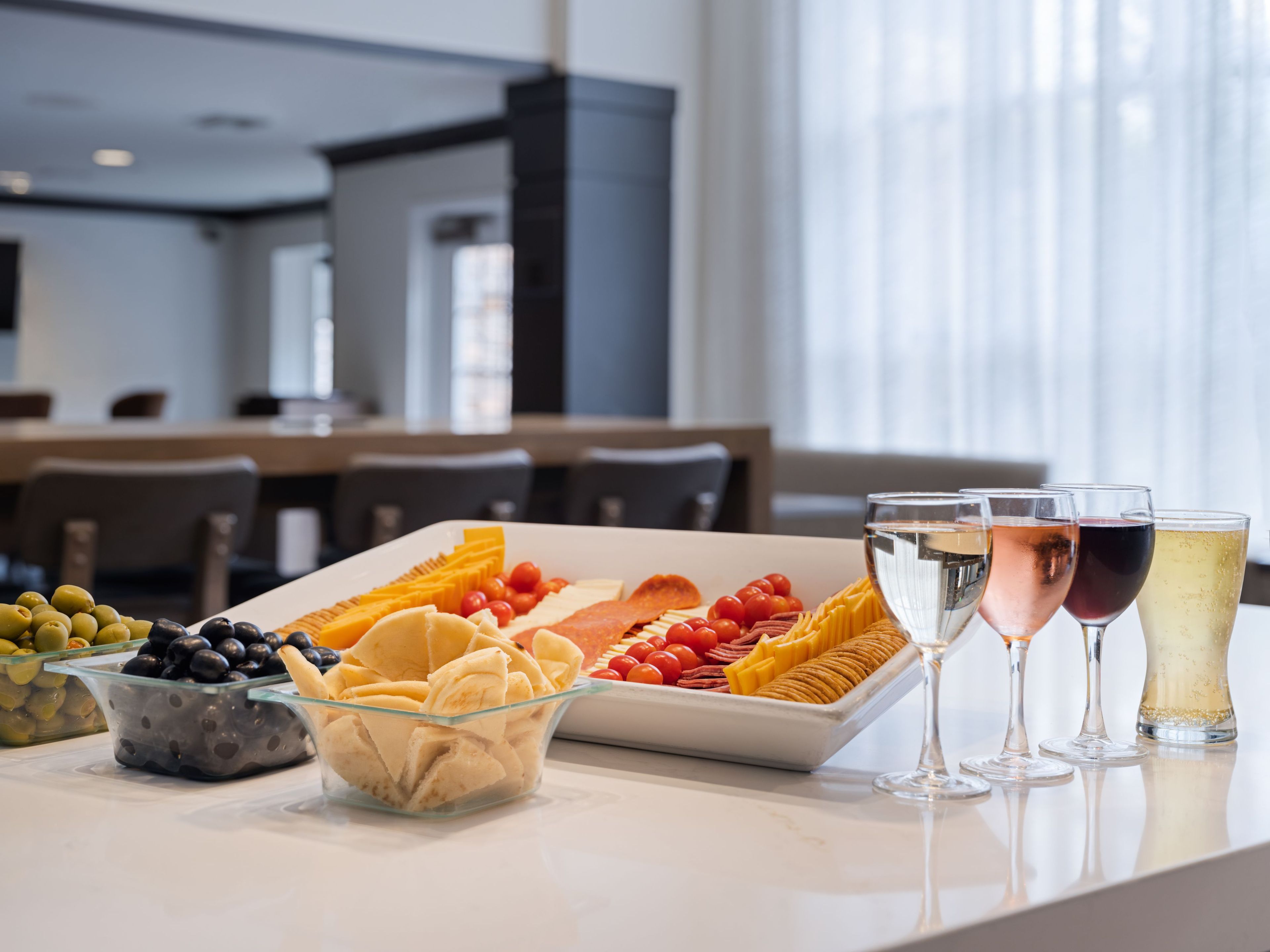 A buffet table with various food items and glasses of beverages.