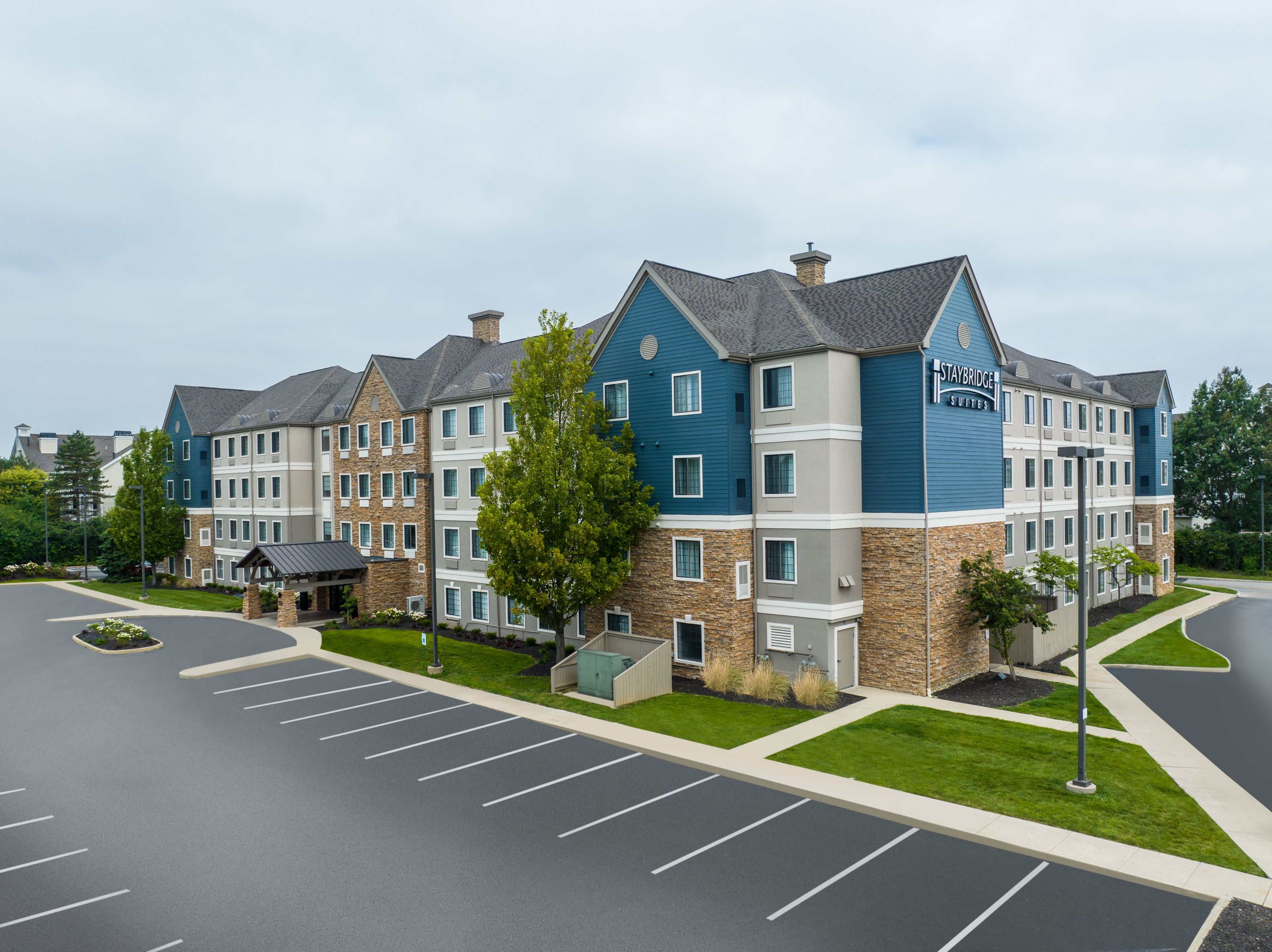 A multi-story hotel with a stone facade, blue and grey exterior, and a parking lot in front.