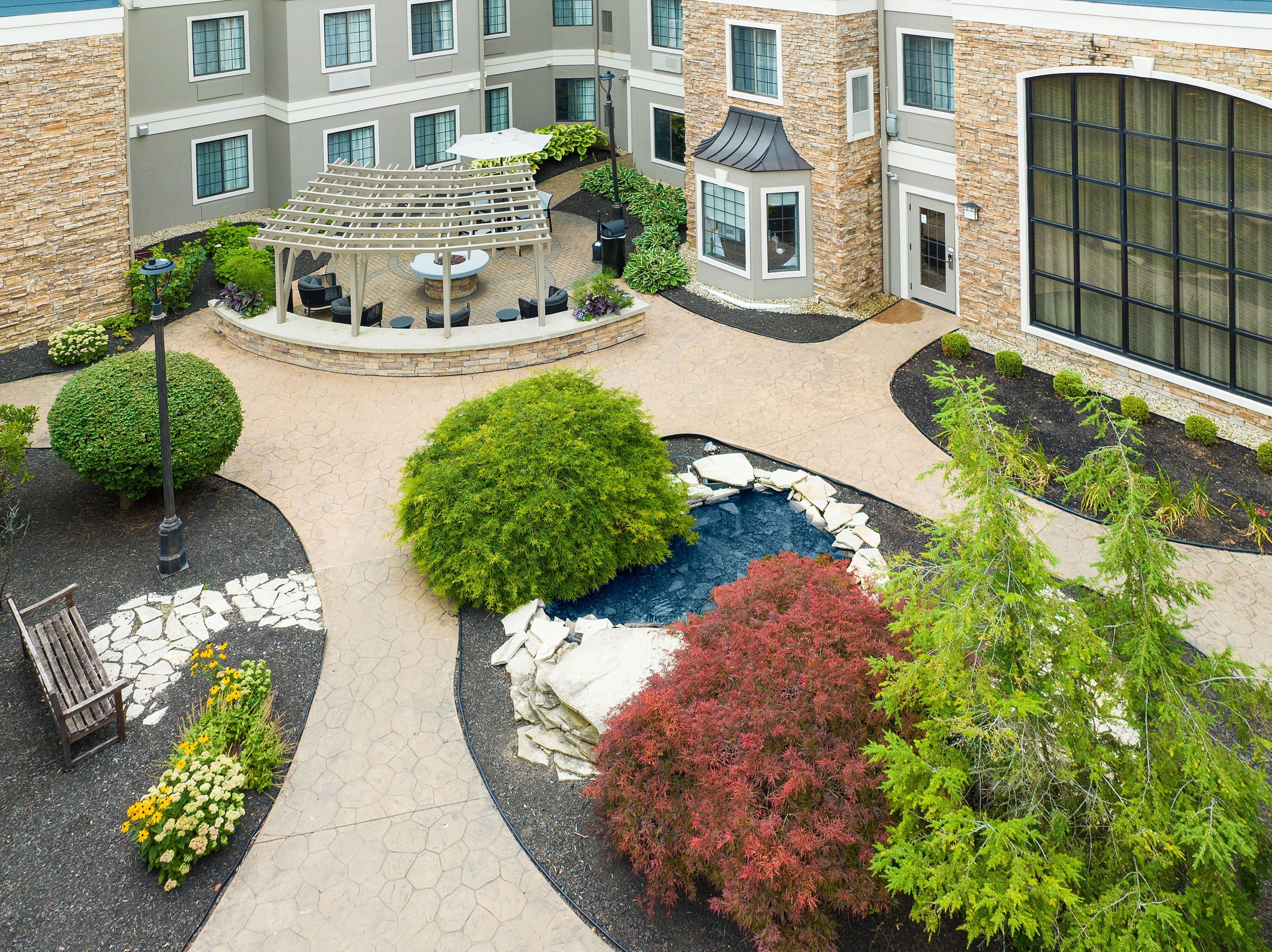 A courtyard with a central fountain, surrounded by a variety of plants and a seating area.