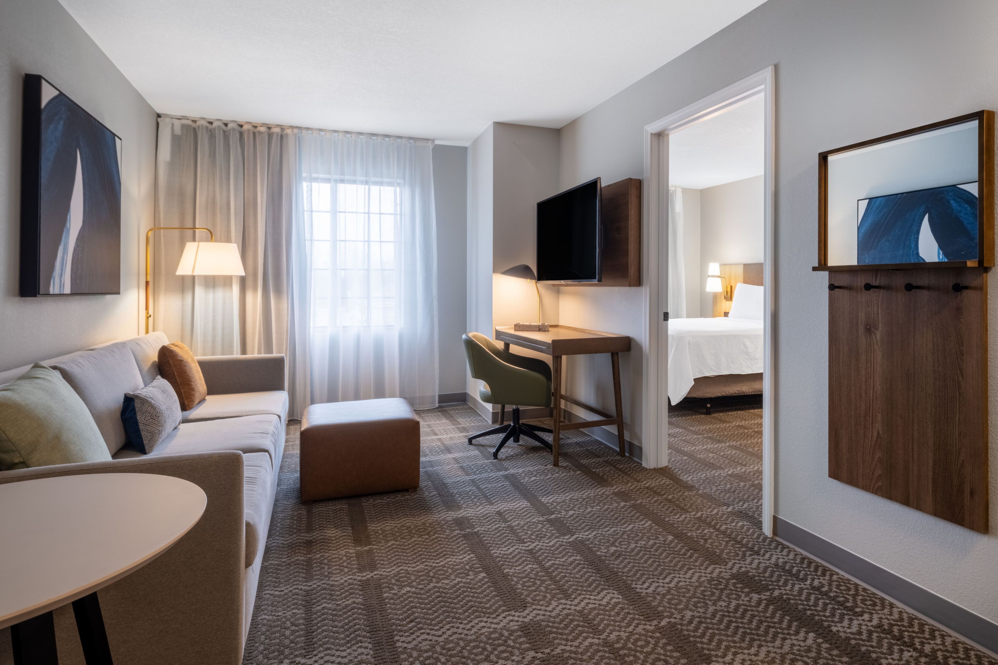 Ett hotellrum med en soffa, ett skrivbord, en tv och en säng.