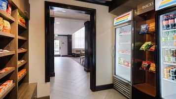 A corridor with snack shelves on the left and a refrigerated snack display on the right.