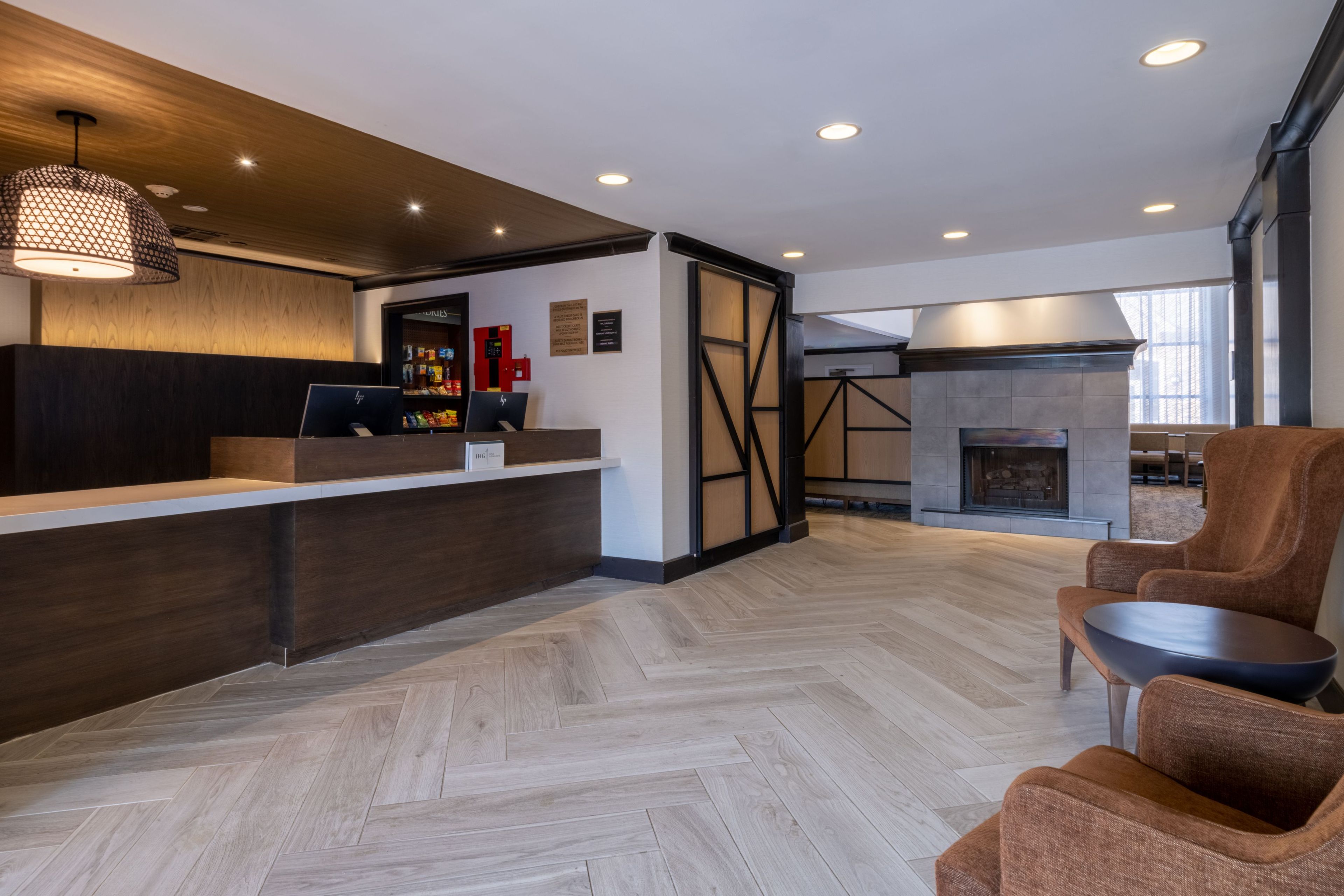 A modern reception area with a wooden reception desk, a fireplace, and seating.