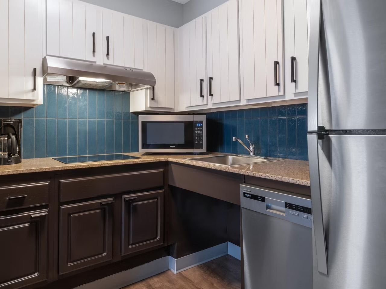 Una cocina moderna con armarios blancos, un refrigerador de acero inoxidable, un microondas y un lavavajillas.