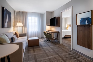 Una habitación de hotel con sofá, escritorio, televisor y cama.