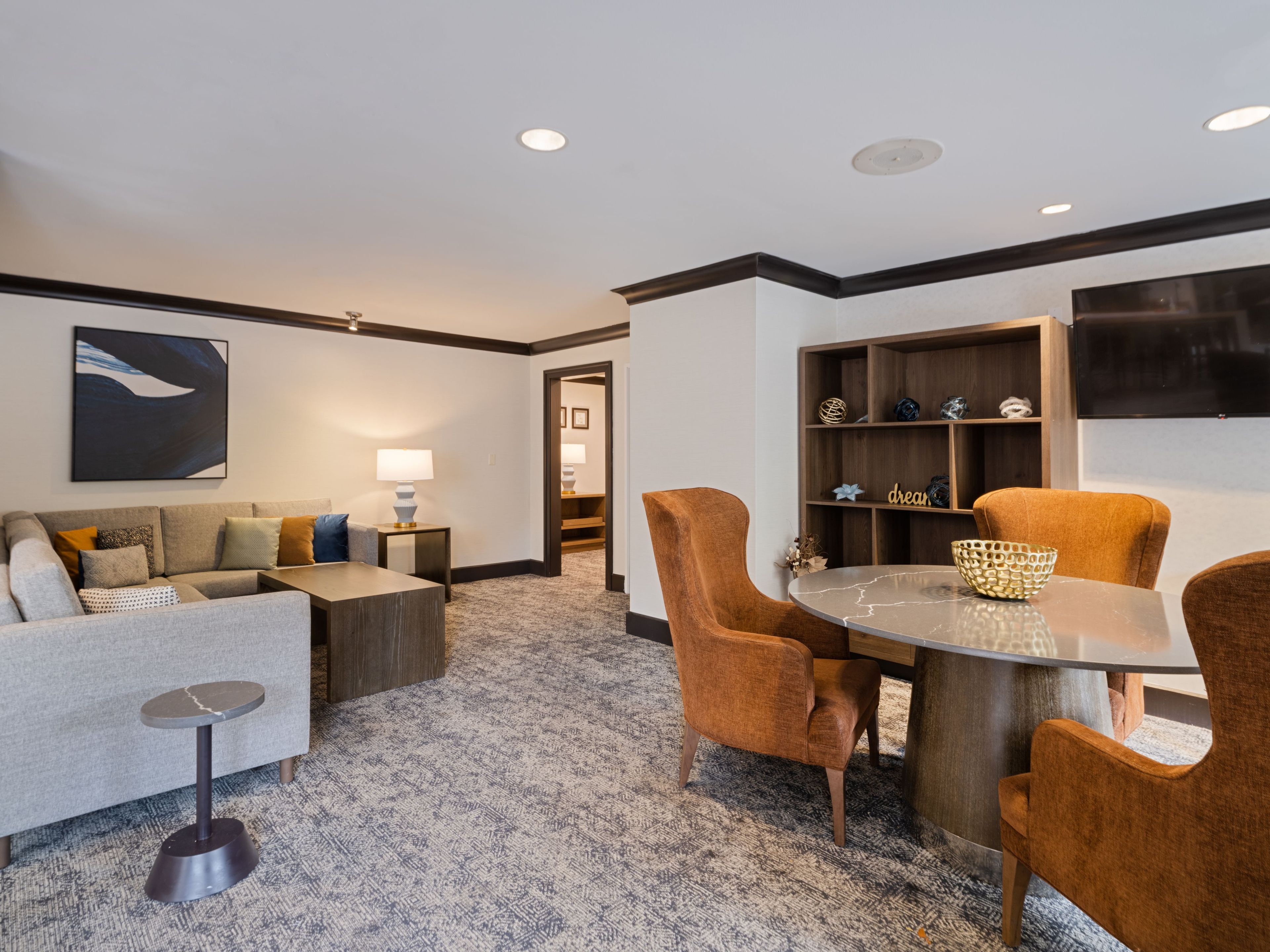 A modern living room with a sofa, armchairs, a coffee table, and a TV mounted on the wall.