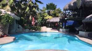A clear blue pool surrounded by tropical vegetation and thatched structures. - Lupe - Suite #1 with 1 king size bed, A/C, fan. Located on ground level. (Coyuca de Benitez)