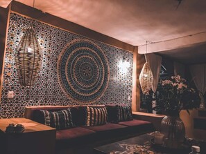 A cozy seating area with a patterned wall, a woven light fixture, and a vase with flowers. - Lupe - Suite #1 with 1 king size bed, A/C, fan. Located on ground level. (Coyuca de Benitez)