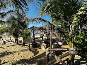 Un décor de plage avec des palmiers, des structures en bois et des chaises longues.