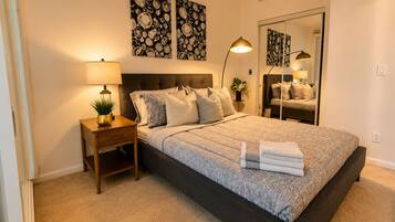 A bedroom with a large bed, bedside tables, a mirror, and artwork on the wall.