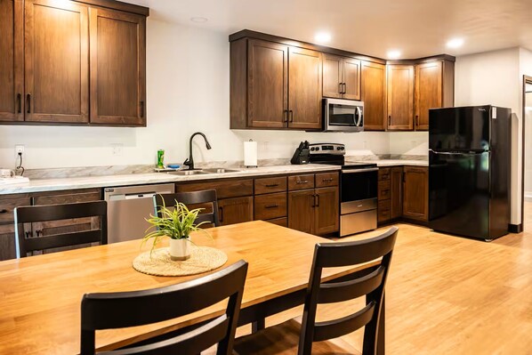 Una cocina moderna con armarios de madera, electrodomésticos de acero inoxidable y una mesa de comedor con sillas.