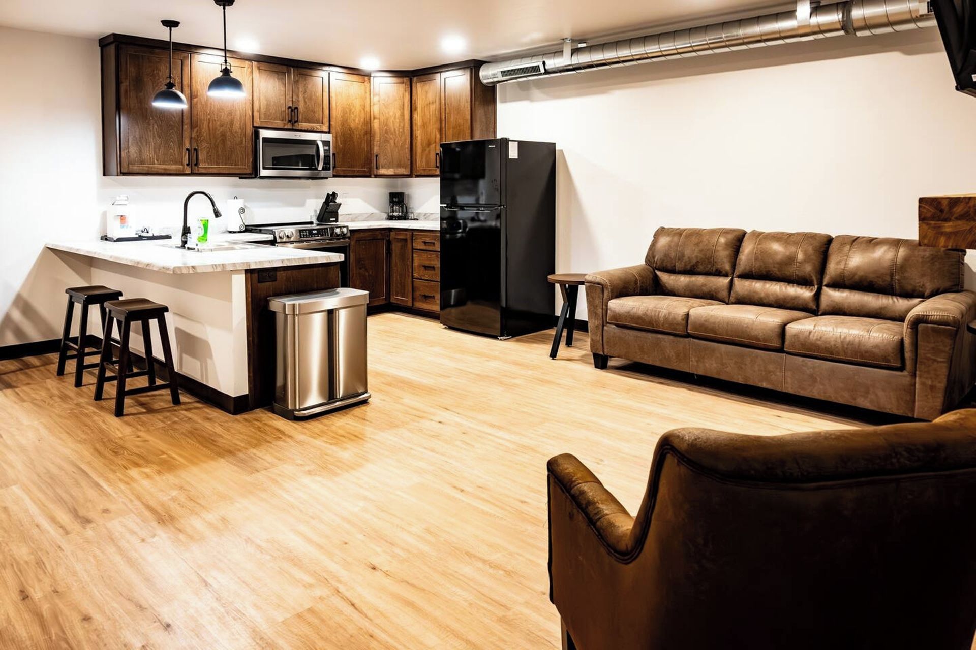 Una cocina moderna con armarios de madera, un refrigerador de acero inoxidable y un microondas integrado.