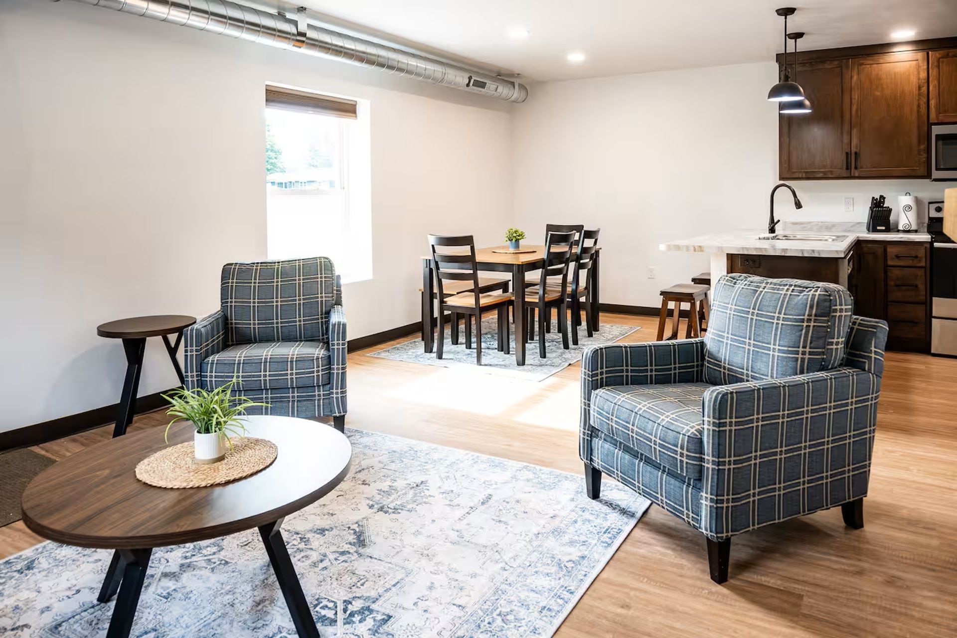 En moderne stue med sofa, et lille bord og et spiseområde med stole.
