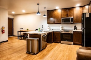 A modern kitchen with wooden cabinets, stainless steel appliances, and a marble countertop. - Exclusive Full-Complex Retreat: Reserve All 7 Suites & Common Areas (Brillion)