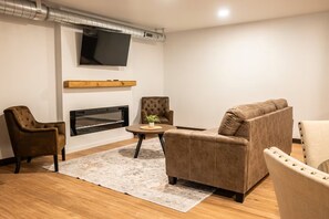 A living room with a flat-screen TV, a fireplace, and leather sofas. - Exclusive Full-Complex Retreat: Reserve All 7 Suites & Common Areas (Brillion)