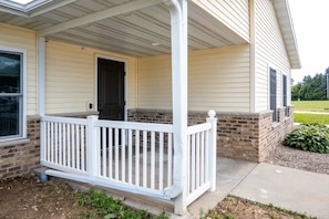 A house with a covered porch, a brick foundation, and a door. - Exclusive Full-Complex Retreat: Reserve All 7 Suites & Common Areas (Brillion)