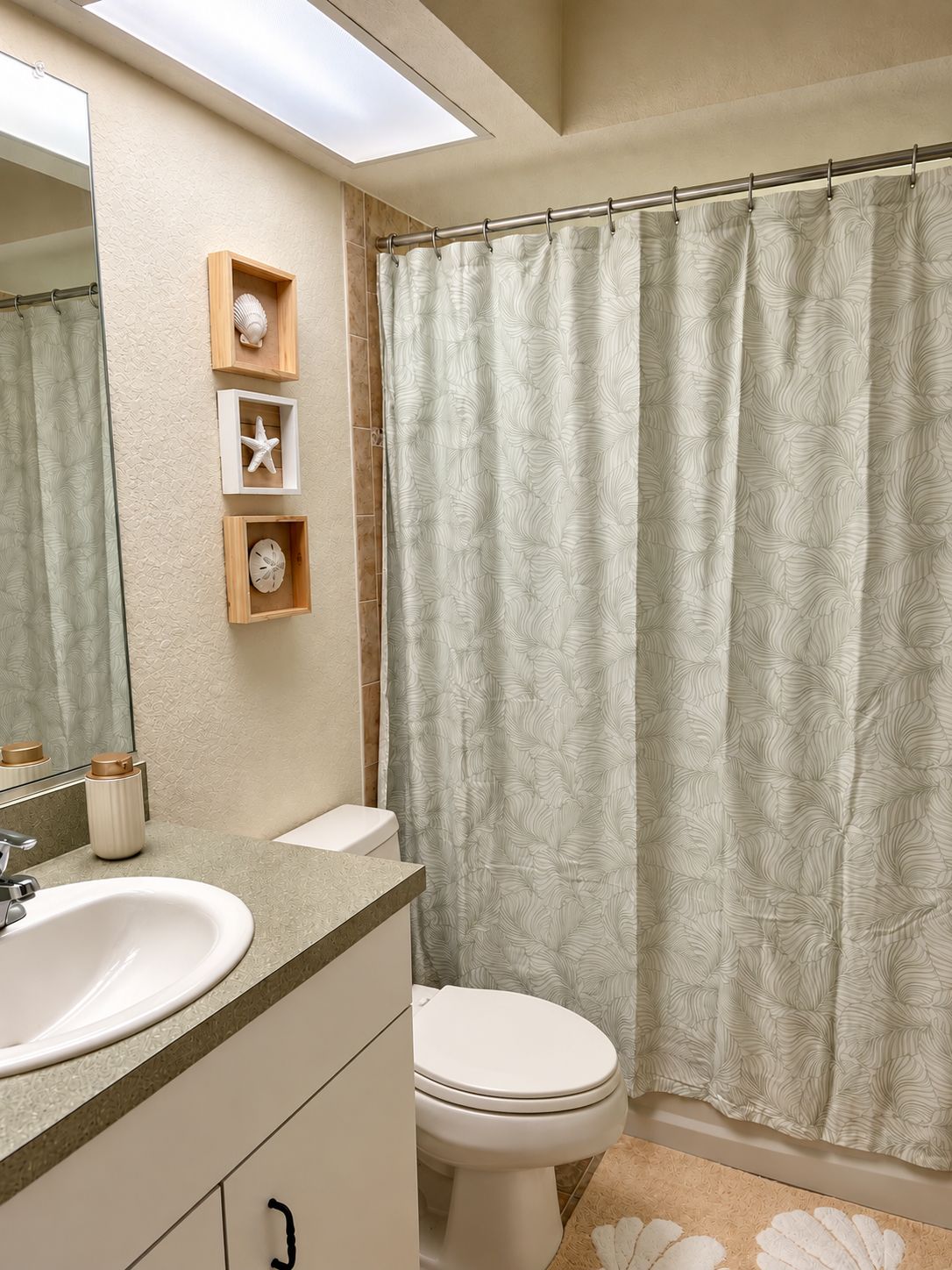 Un baño con un espejo grande, un inodoro, un lavamanos y una cortina de ducha.