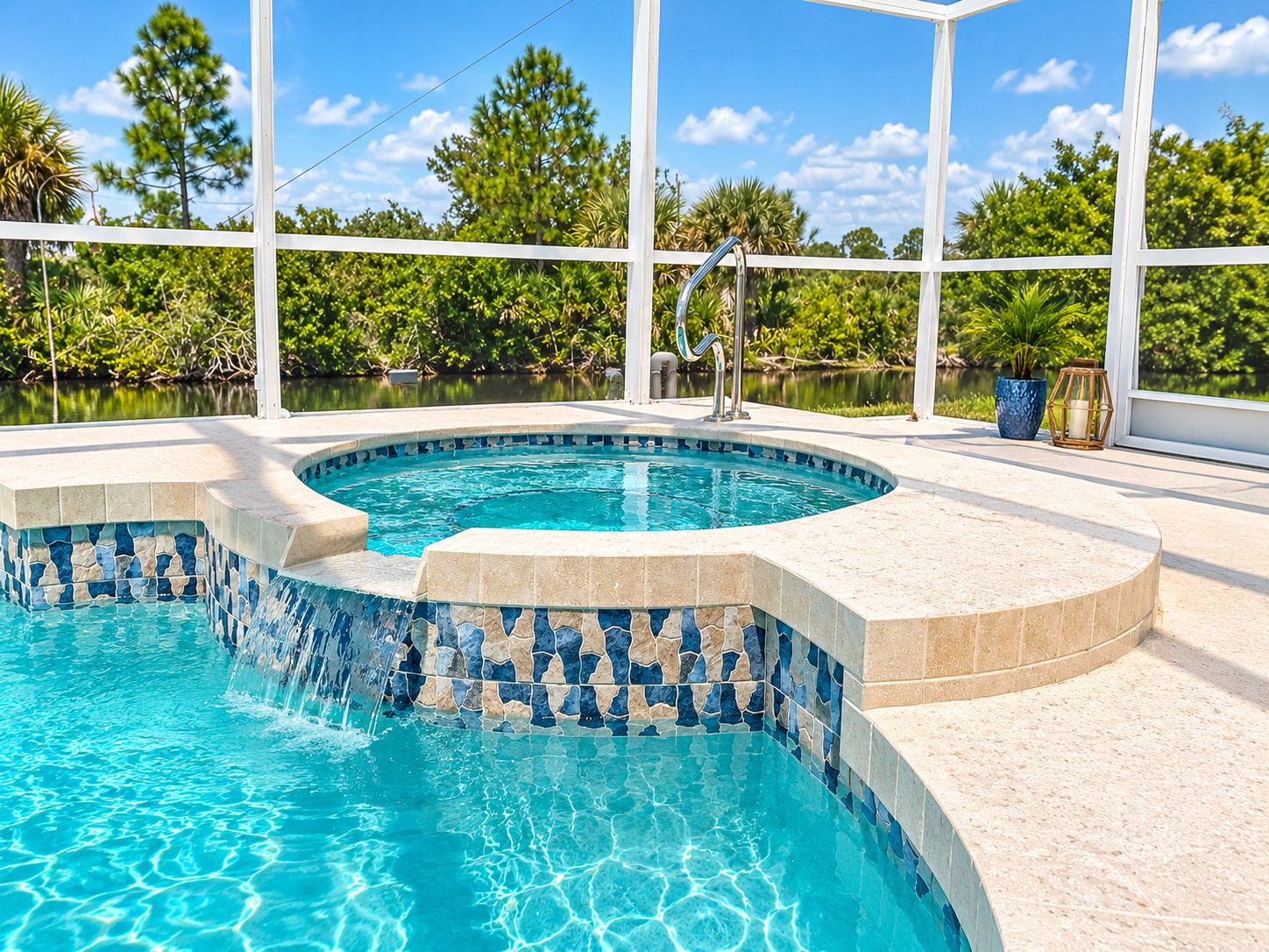 A swimming pool with a tiled edge, surrounded by a covered area with a view of trees and a body of water.