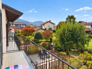 Un balcon donnant sur un quartier résidentiel, avec des maisons et une montagne en arrière-plan.