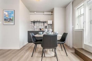 A dining area with a round table, black chairs, and a kitchen in the background. - Welcome Apartments (Reykjavik)