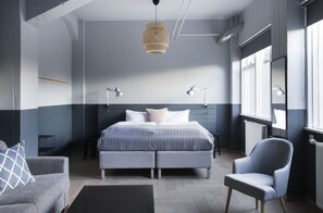 A modern bedroom with a large bed, two bedside lamps, a chair, and a hanging light fixture. - Welcome Apartments (Reykjavik)