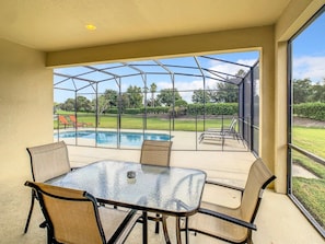 Un patio cubierto con cerramiento de vidrio, piscina y mobiliario exterior.