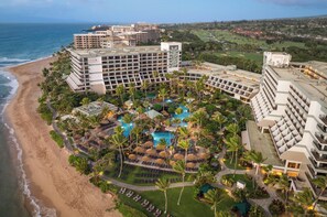 Un resort con varias edificaciones, una playa y una zona de piscina.