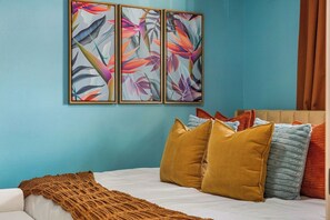 Una camera da letto con un letto, cuscini, una coperta e un quadro appeso al muro.