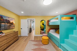 A room with a bunk bed, a wooden dresser, a painting, and a staircase. - Largo Family Home with Pool & Mini Golf (largo)