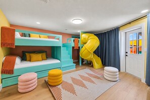 Ein Kinderzimmer mit Stockbetten, einer Rutsche und einer Tür mit Vorhängen.