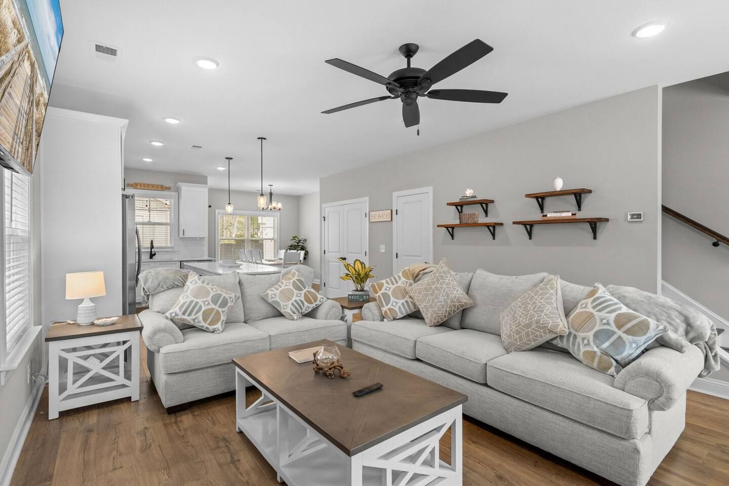 A modern living room with a sectional sofa, a coffee table, and a ceiling fan.