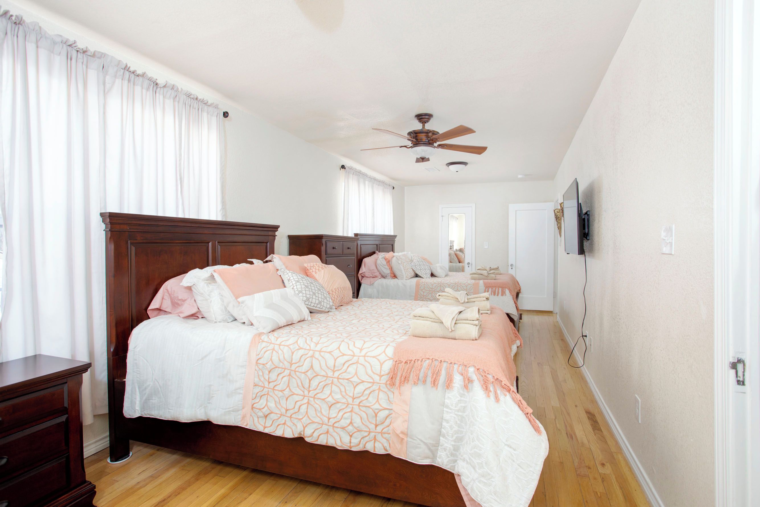 A bedroom with a large bed, a ceiling fan, and a wooden dresser.