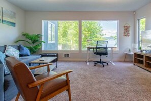 A living room with a sofa, a wooden chair, a desk with a chair, and a television. - Panoramic Lake View 3800+ sqft House in Oasis (Seattle)