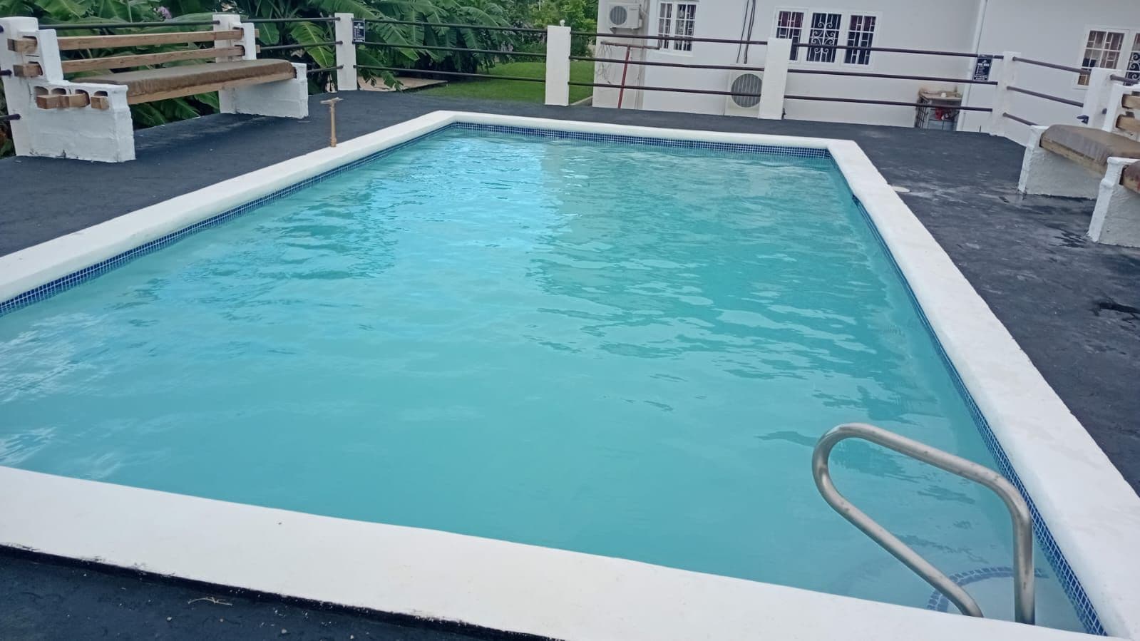 Une piscine rectangulaire avec une échelle métallique sur l’un des côtés.